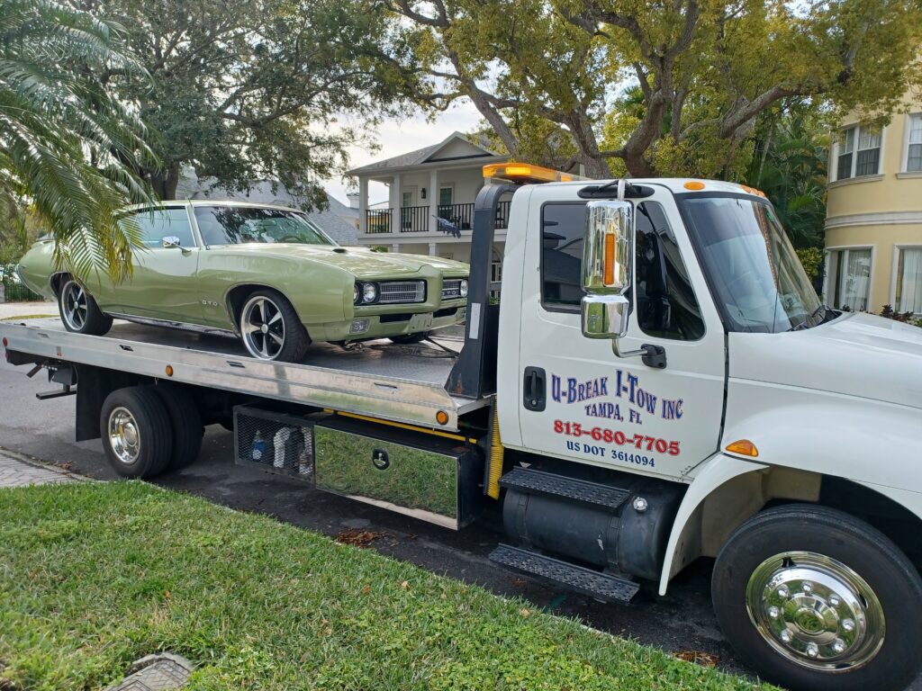 A green classic car towed on a tow truck