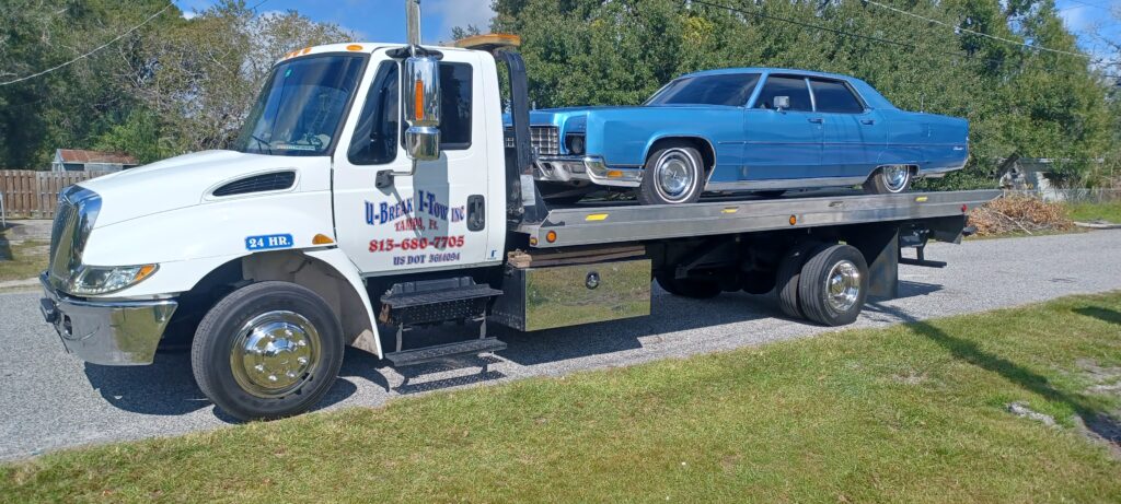 A blue classic car towed on a towing truck