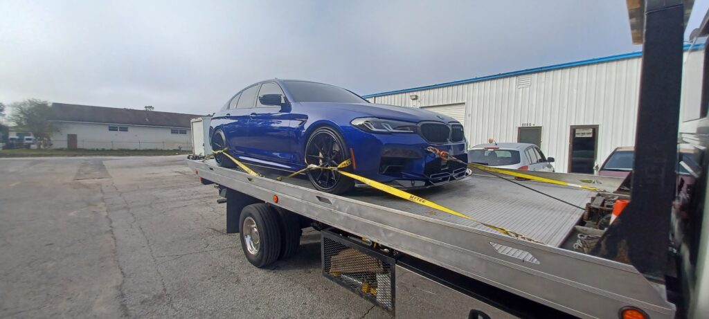 A blue BMW towed on a tow truck