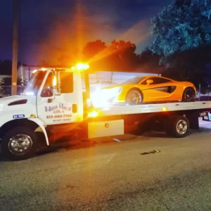 An orange Ferrari towed on a tow truck